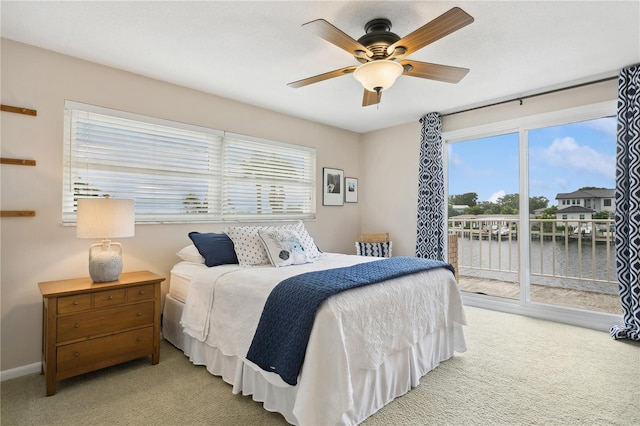 bedroom featuring light carpet, access to outside, multiple windows, and a water view