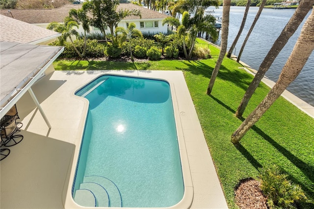 outdoor pool with a water view and a yard