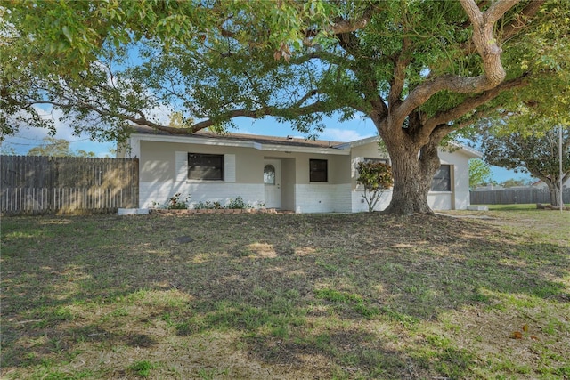 single story home with a front lawn, fence, and brick siding