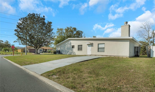 view of front facade with stucco siding, a front lawn, fence, cooling unit, and a chimney