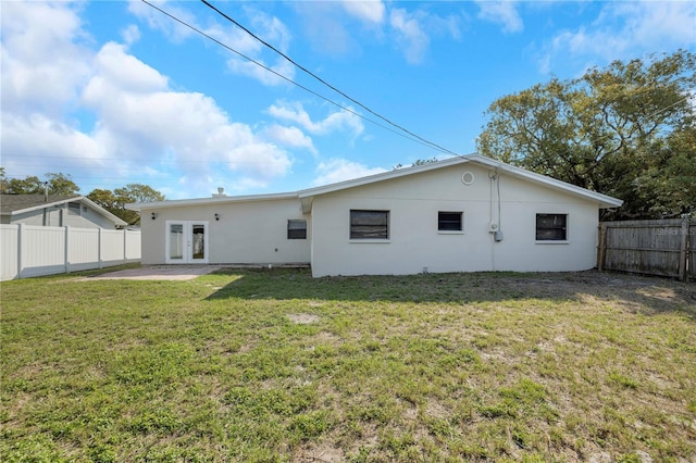 back of house with a lawn, french doors, stucco siding, a fenced backyard, and a patio