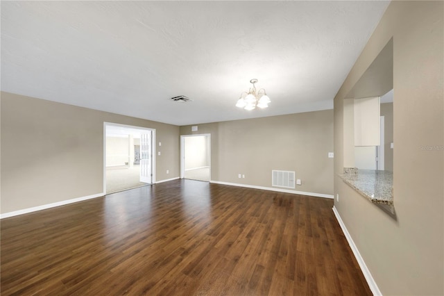 unfurnished living room with a notable chandelier, baseboards, visible vents, and dark wood-style flooring