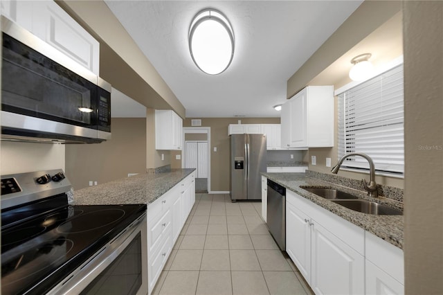 kitchen with light tile patterned floors, light stone countertops, appliances with stainless steel finishes, and a sink