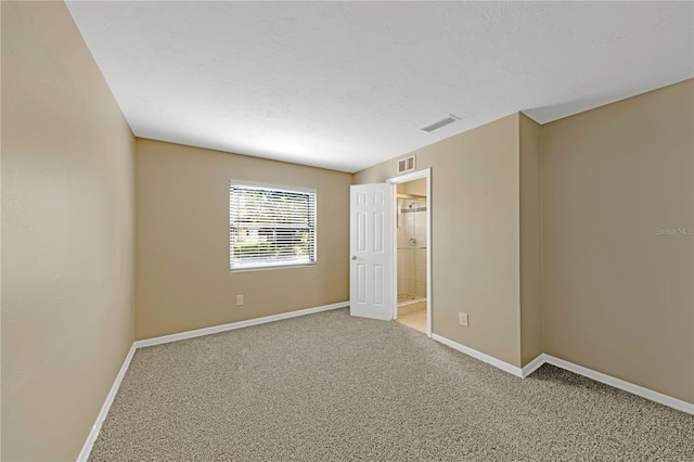 unfurnished bedroom featuring visible vents, light colored carpet, a textured ceiling, and baseboards