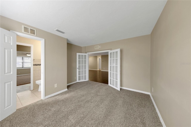 unfurnished bedroom with carpet flooring, french doors, baseboards, and visible vents