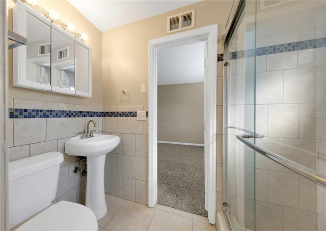 bathroom featuring tile patterned floors, visible vents, a stall shower, and tile walls