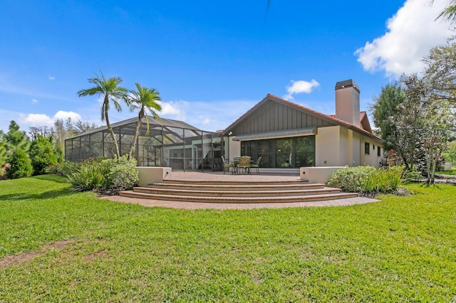 rear view of property with a lanai, a chimney, and a lawn