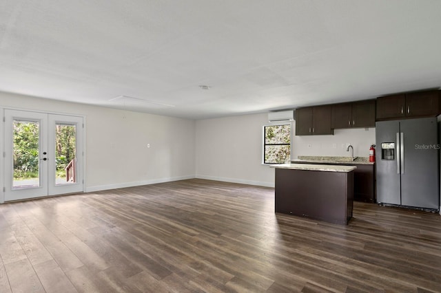 kitchen featuring dark brown cabinetry, stainless steel fridge, dark wood finished floors, a center island, and light countertops