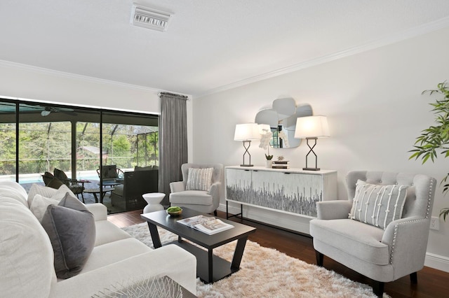 living area featuring ornamental molding, visible vents, baseboards, and wood finished floors