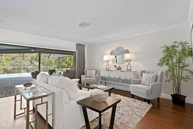 living room with baseboards, visible vents, a sunroom, ornamental molding, and wood finished floors