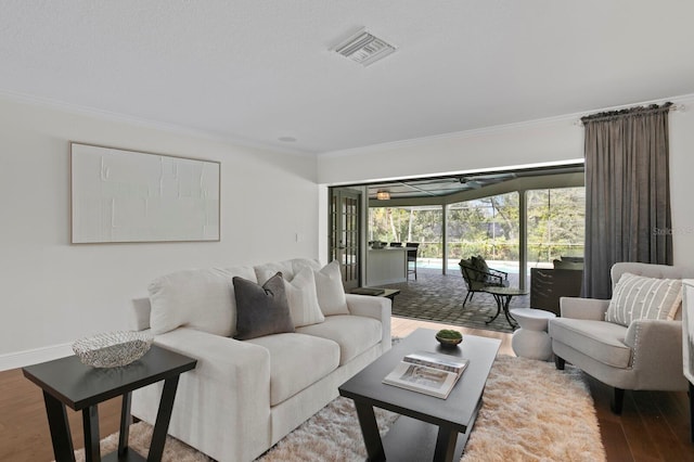 living area with visible vents, baseboards, a sunroom, wood finished floors, and crown molding