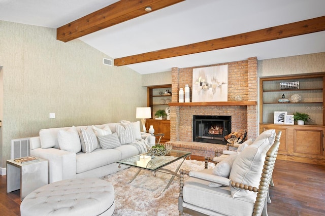 living area featuring lofted ceiling with beams, a brick fireplace, wood finished floors, and visible vents