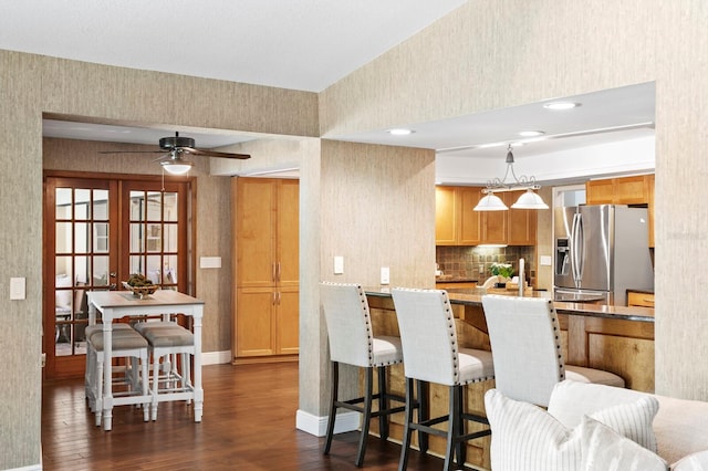 kitchen featuring baseboards, stainless steel fridge with ice dispenser, a kitchen breakfast bar, dark wood-type flooring, and french doors