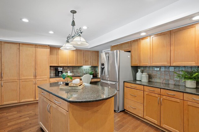 kitchen with recessed lighting, wood finished floors, a kitchen island, backsplash, and stainless steel fridge