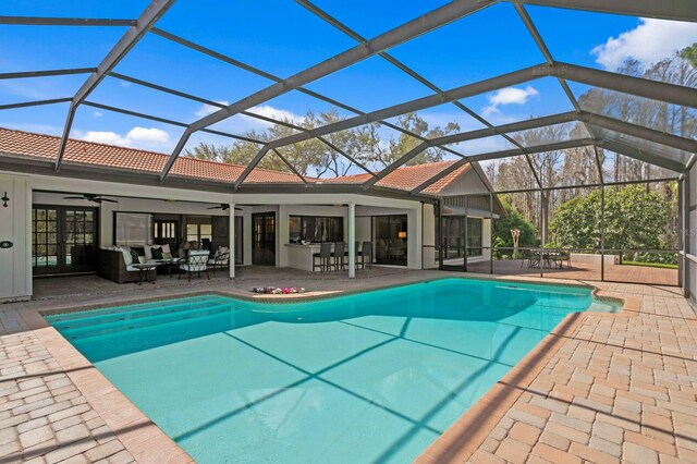 pool featuring glass enclosure, french doors, a patio area, and ceiling fan