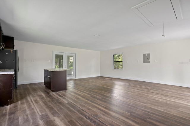 unfurnished living room with attic access, electric panel, dark wood-type flooring, and french doors