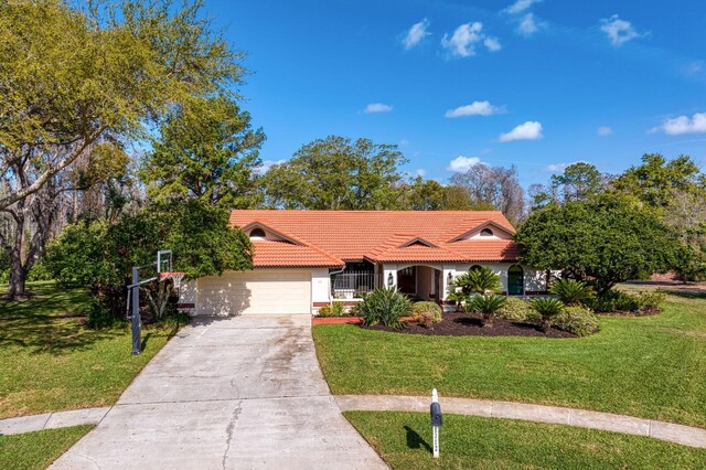 view of front facade with a garage, driveway, a front lawn, and a tile roof