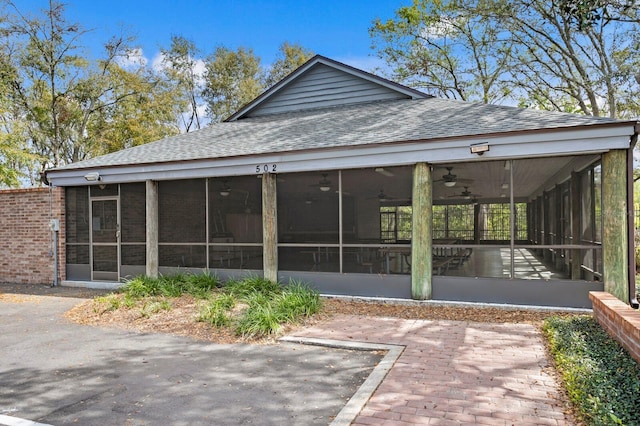 back of property featuring roof with shingles and a sunroom