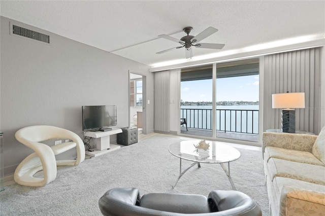 living area with ceiling fan, a textured ceiling, carpet, and visible vents