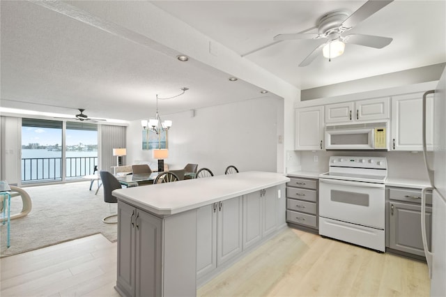 kitchen featuring gray cabinets, white appliances, light countertops, and open floor plan