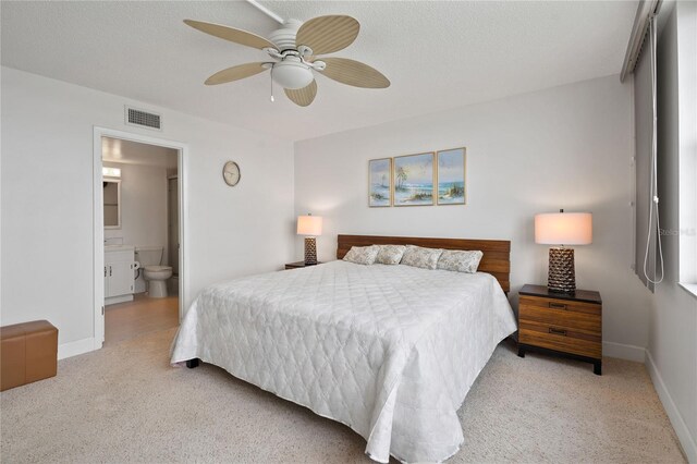 bedroom featuring light carpet, baseboards, visible vents, connected bathroom, and a textured ceiling