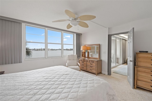 carpeted bedroom featuring ceiling fan and a water view