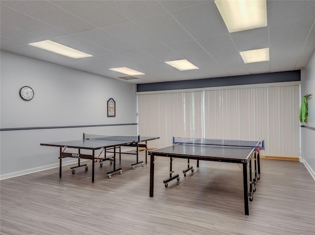 playroom with wood finished floors, a paneled ceiling, and baseboards