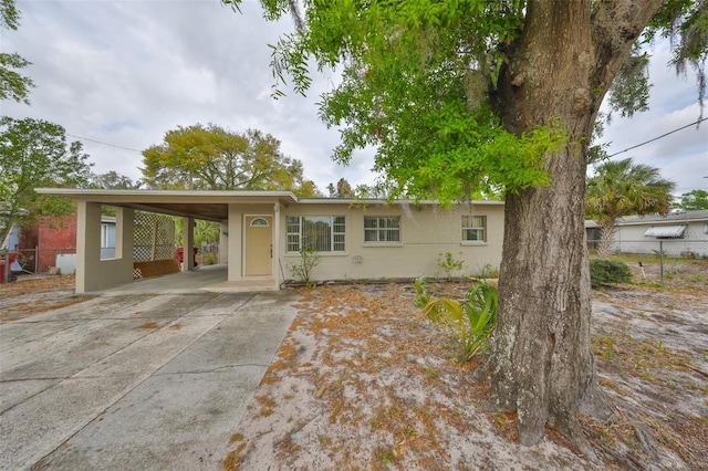 ranch-style house with stucco siding, a carport, concrete driveway, and fence