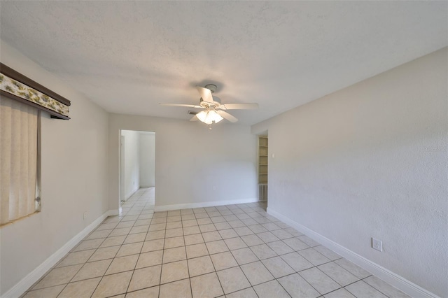 unfurnished room with a textured ceiling, light tile patterned flooring, baseboards, and ceiling fan