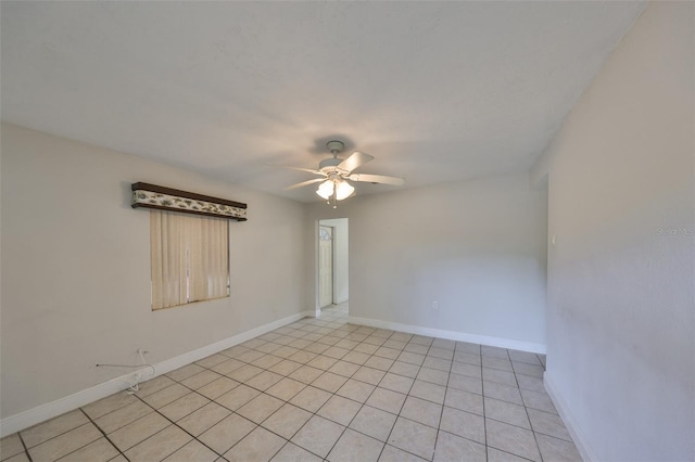 empty room featuring light tile patterned flooring, a ceiling fan, and baseboards