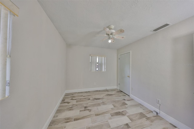 spare room featuring visible vents, baseboards, a textured ceiling, and ceiling fan