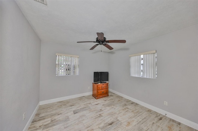 spare room featuring a wealth of natural light, baseboards, a textured ceiling, and wood finished floors