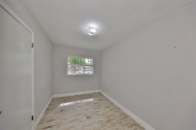 empty room with baseboards, a textured ceiling, and wood finished floors