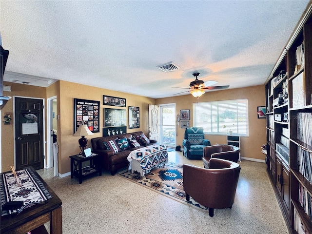 living area with visible vents, a textured ceiling, baseboards, and speckled floor