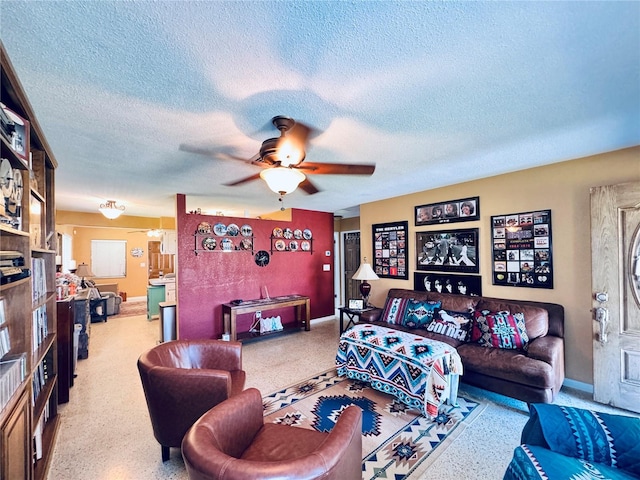 living area with ceiling fan, a textured ceiling, and speckled floor