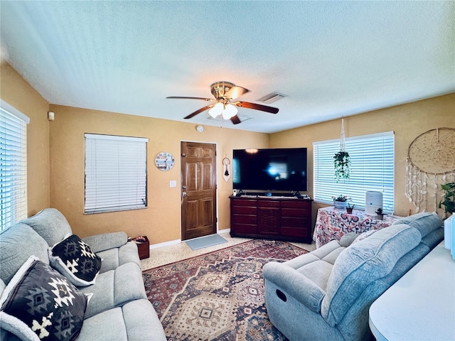 living area with a textured ceiling, a wealth of natural light, visible vents, and baseboards