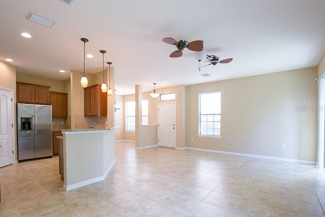 kitchen with brown cabinets, visible vents, decorative backsplash, light stone countertops, and stainless steel fridge with ice dispenser