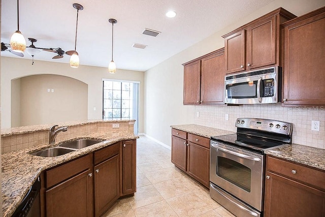 kitchen with stone countertops, visible vents, a sink, stainless steel appliances, and backsplash