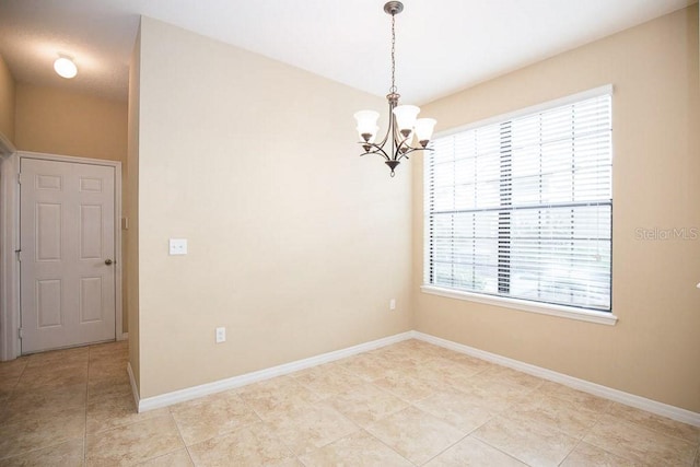 empty room with a chandelier and baseboards