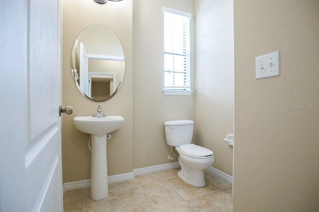 half bathroom featuring baseboards, toilet, and tile patterned floors