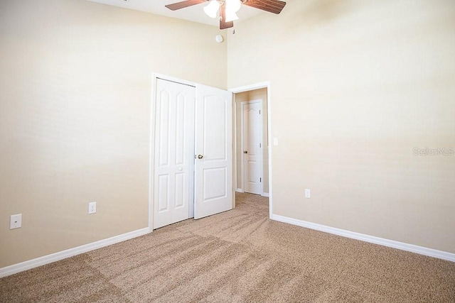 unfurnished room featuring high vaulted ceiling, a ceiling fan, baseboards, and carpet flooring