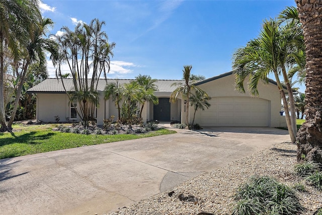 view of front of property with concrete driveway, a tile roof, an attached garage, and stucco siding