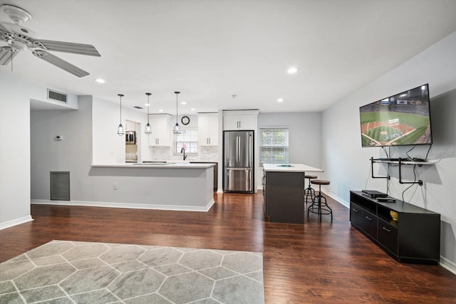 kitchen featuring tasteful backsplash, a kitchen breakfast bar, dark wood finished floors, and freestanding refrigerator