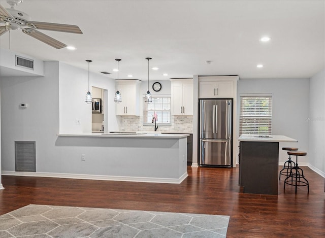 kitchen featuring visible vents, appliances with stainless steel finishes, a breakfast bar, and dark wood-type flooring