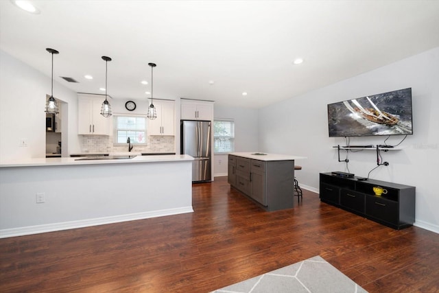 kitchen with white cabinets, dark wood-style flooring, freestanding refrigerator, light countertops, and backsplash