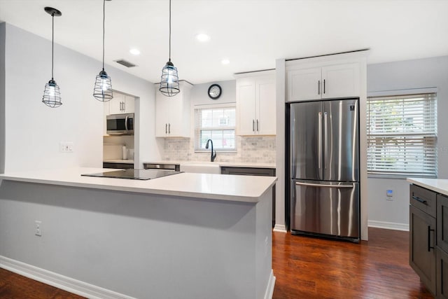 kitchen featuring stainless steel appliances, a sink, white cabinets, decorative backsplash, and dark wood-style floors