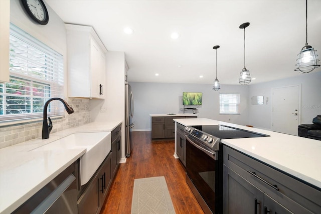 kitchen with stainless steel appliances, dark wood-type flooring, a sink, light countertops, and backsplash