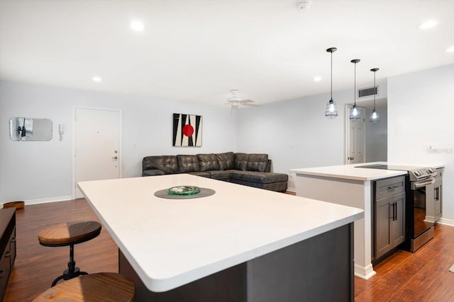 kitchen featuring dark wood-type flooring, a center island, visible vents, and stainless steel electric stove