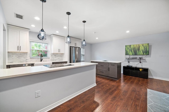 kitchen with tasteful backsplash, visible vents, appliances with stainless steel finishes, dark wood-style flooring, and light countertops