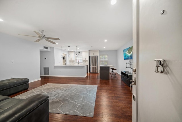 living room featuring ceiling fan, baseboards, visible vents, and dark wood finished floors